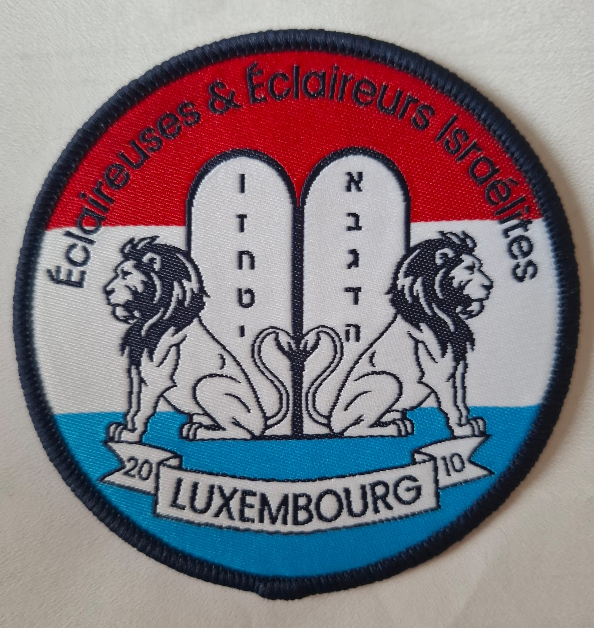 Écusson EEIL des 15 ans : deux lions gardant les Tables de la Loi sur les couleurs du Luxembourg, Luxembourg 2010